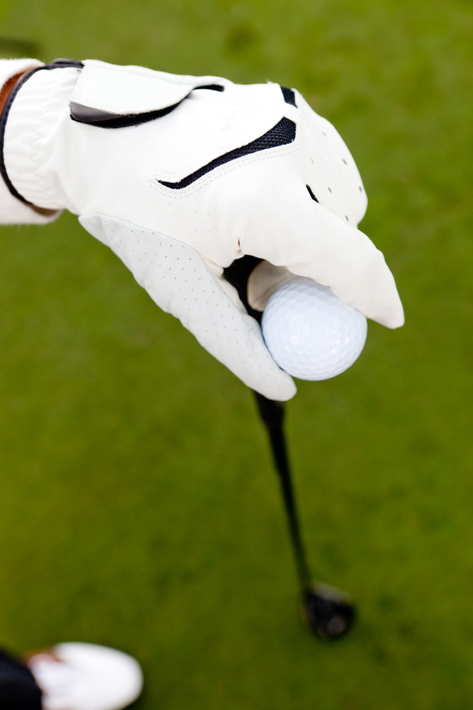 Close-up of a hand wearing a glove and holding a golf club Close-up of a hand wearing a glove and holding a golf club