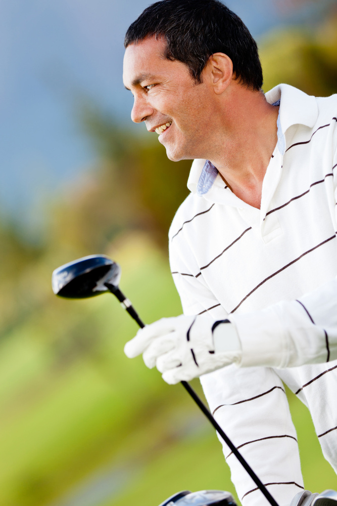 Male golf player holding a golf-club at the course Male golf player holding a golf-club at the course