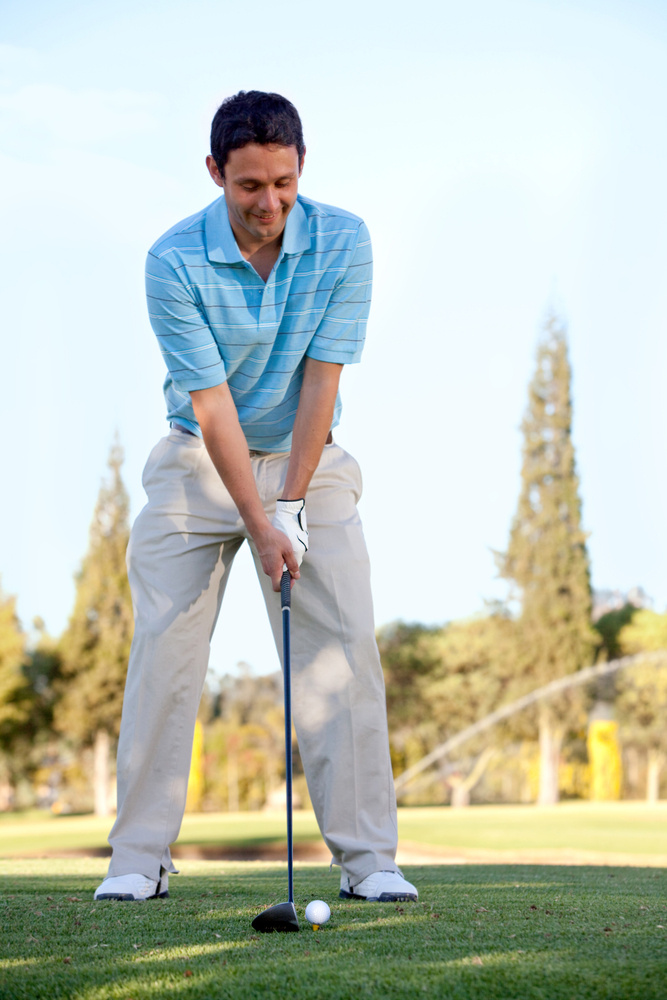 Young man playing golf leaning on the club and smiling Young man playing golf leaning on the club and smiling